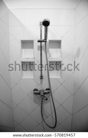 Wall shower install on white tile wall in bathroom for body wash, there are have small four function on wall for put bath accessories. Royalty-Free Stock Photo #570819457