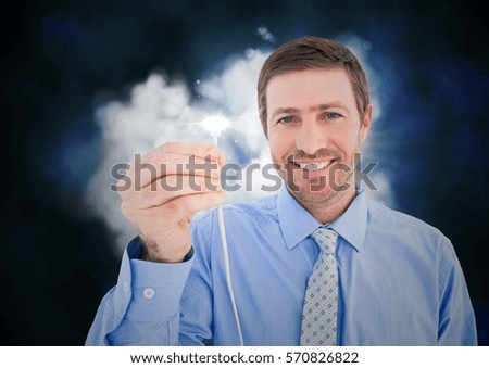 Portrait of businessman holding cable with flare against digitally generated cloud background