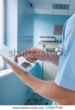 Mid section of doctor using digital tablet in hospital