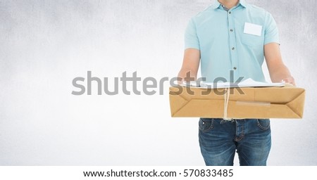 Mid section of delivery man holding box against grey background