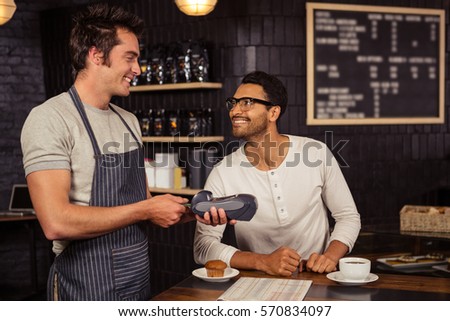 Man paying his coffee with credit card in a coffee shop