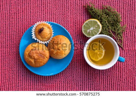 Breakfast time. Cup of lemon tea and homemade muffins on blue plate. Food background.