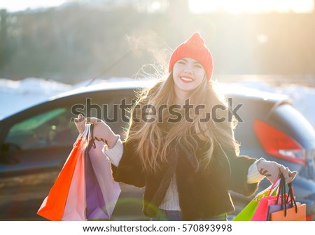 Smiling Caucasian woman holding her shopping bag near the car - shopping concept
