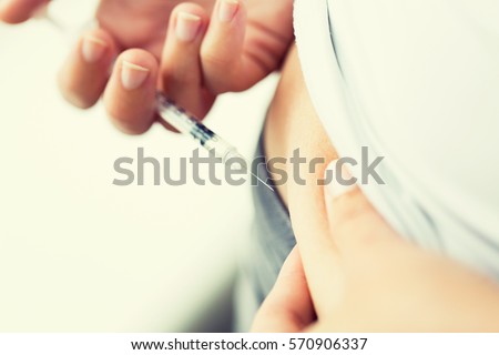 medicine, diabetes, glycemia, health care and people concept - close up of woman with syringe making insulin injection to himself at home Royalty-Free Stock Photo #570906337