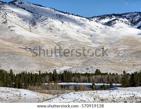 A frozen pond, snow covered hills and a perfect blue sky in the background.