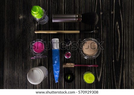 Colorful set of makeup products - foundation, lip gloss, blush, eyeshadow, concealer, face cream, primer, brush, nail polish on natural wooden background.