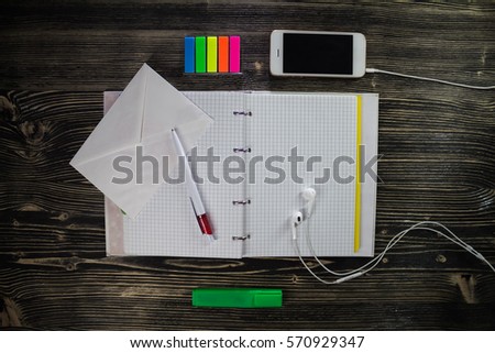 Opened notepad with envelope and headphone with phone.