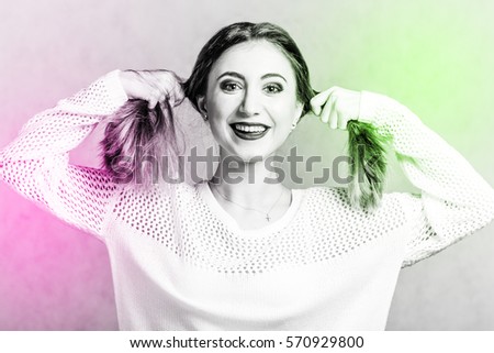 Happy young woman in a white sweater over grey background