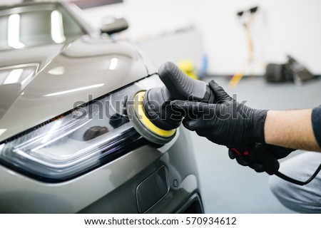 Car detailing - Hands with orbital polisher in auto repair shop. Selective focus. Royalty-Free Stock Photo #570934612