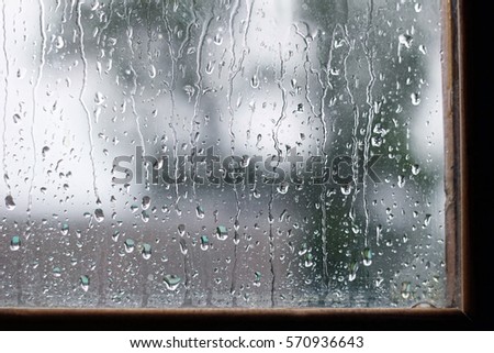drops water on wet glass window in rainy day. rain outside window. summer or autumn rainy season. abstract texture of raindrops close up