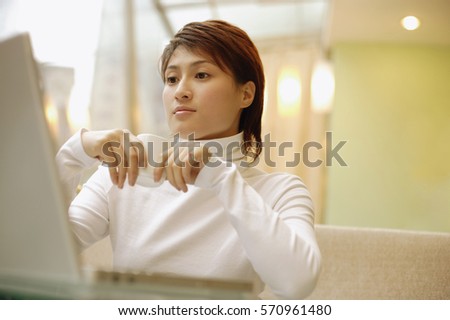 Young woman wearing white turtleneck, using laptop