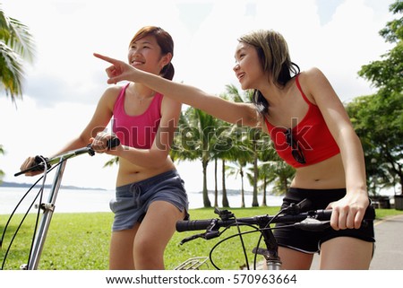 Two women on bicycles, one woman pointing