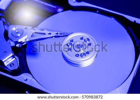 Close up hard disk's internal mechanism hardware. Detail of writing/reading . Blue Toned Image