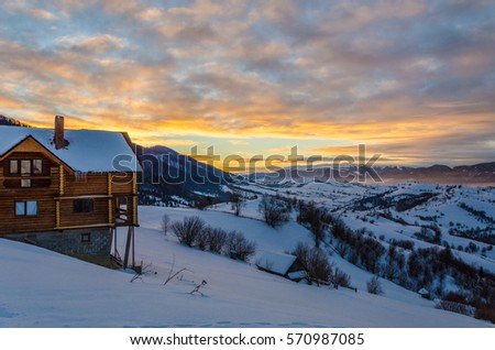 Wooden house on a mountain slope in snow Blue Christmas hhory of forest in the background Winter landscape.