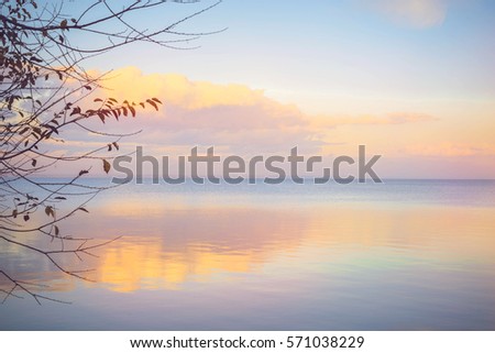Sky background on sunset. Nature composition. Panoramic sunset sky background. Sunrise sky with lighted clouds. Beautiful sunset over sea with reflection in water, majestic clouds in the sky.