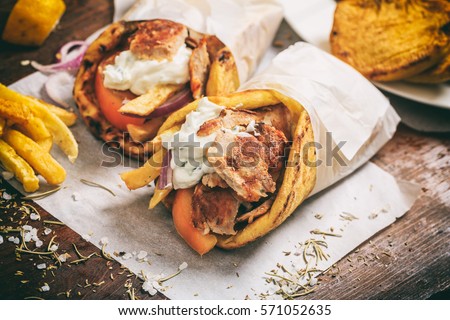 Gyros souvlaki wrapped in a pita bread on a wooden background Royalty-Free Stock Photo #571052635