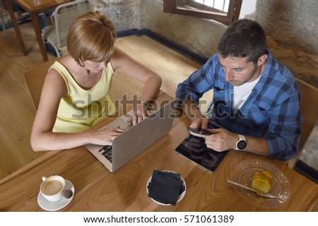 young American couple at coffee shop with man and woman close up hands using laptop computer and mobile phone networking ignoring each other in relationship communication problem