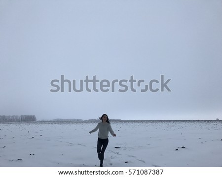Happy girl running and dancing in a winter field. Hipster in the forest.Winter vacation.Traveler.Black jacket and black jeans.Hipster style. Time to relax. On the road.Perfect body. ballerina dancing