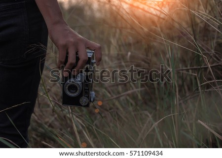 Woman holding a camera in the field.