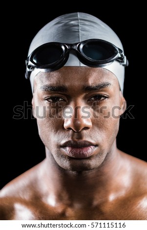 Portrait of swimmer in swimming goggles and swimming cap on black background
