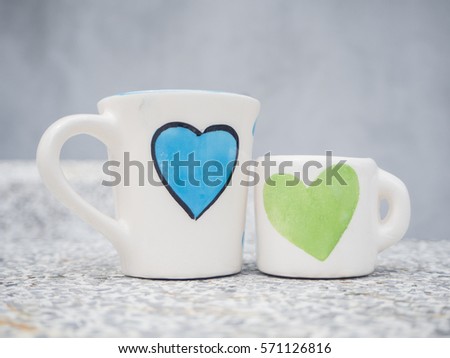two white cups and size on marble table with blue and green heart printed