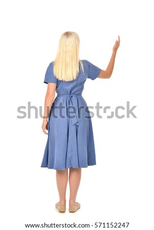 full length portrait of a blonde haired woman wearing a simple blue dress.
standing pose with back to the camera, isolated on white background.