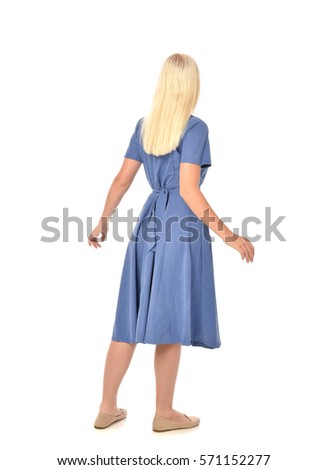 full length portrait of a blonde haired woman wearing a simple blue dress.
standing pose with back to the camera, isolated on white background.