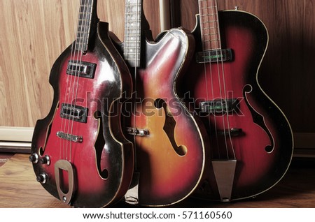 Three vintage bass guitars.Wooden background.