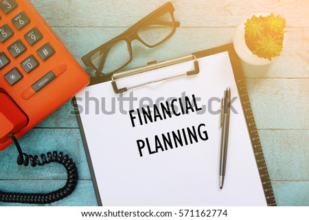 Top view of clipboard and white sheet written with FINANCIAL PLANNING on blue wooden background. Business Concept.