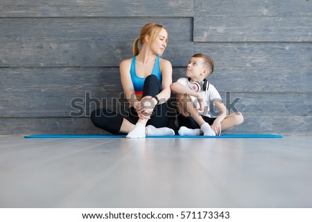 Fitness mother with her 9 years old son. Sports mom with kid relaxing after morning work-out at home. Mum and child do the exercises together, healthy family lifestyle concept Royalty-Free Stock Photo #571173343