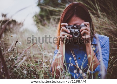 Happy young hipster woman with vintage camera in field. Enjoy with nature sunset, Vintage hipster woman photographer.
