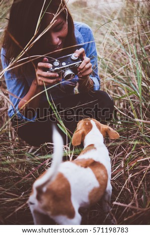 Shot of hipster woman taking a snapshot of her dog on her vintage camera.