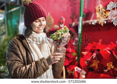 Happy cheerful positive girl buying floral compositions at Christmas market