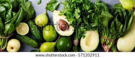 Green vegetables and herbs assortment on a grey stone background. Top view Royalty-Free Stock Photo #571202911