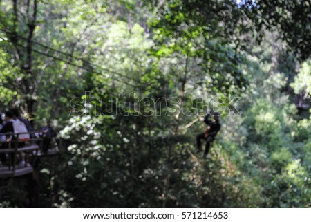 Blurred traveler  hung on a a wire rope over a  forest on a jungle zip line adventure 