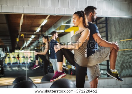 Young athletes exercising and stretching legs at the gym. Royalty-Free Stock Photo #571228462