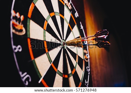 Success hitting target aim goal achievement concept background - three darts in bull's eye close up. red three darts arrows in the target center business goal concept Royalty-Free Stock Photo #571276948