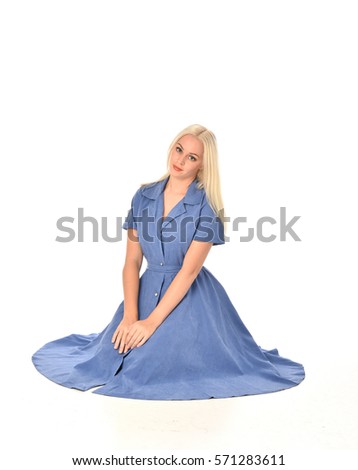 full length portrait of a blonde haired woman wearing a simple blue dress.
kneeling pose  isolated on white background.
