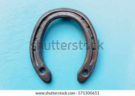 Single old rustic horse shoe on blue chalk painted blue wooden timber