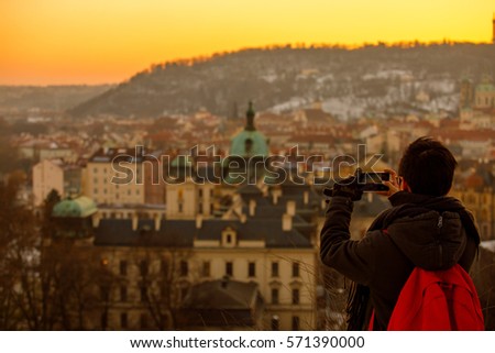 Photographer is holding a cell phone while taking a picture at the Prague panorama from Petrin tower