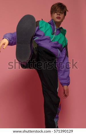 A guy hipster  in a sports suit posing on a pink background