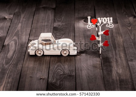 Valentines Day background with wooden toy car and hearts on wooden background 