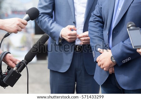 Journalists holding microphones conducting media interview. News conference.