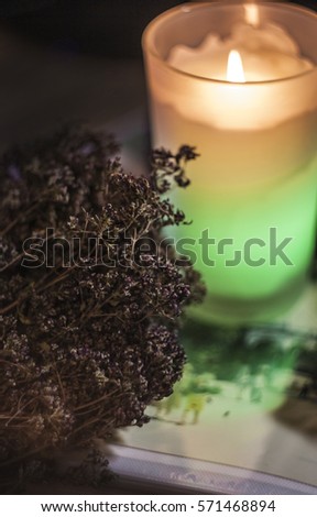 candle burning in the dark, on a background of old pictures and a bouquet of dried flowers