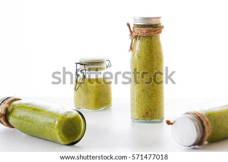 Mix green fruit & vegetable juice made from kiwi & green lettuce in glasses bottle wrapped by hemp rope laying on white table, raw organic fruit juice for healthy people and for weight loss