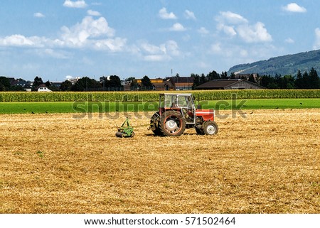 Tractor with plough doing some agricultural seasonal work at the field.