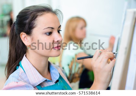 beautiful young girls draws a picture paints on art lesson