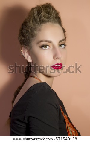 Woman with creative braid hairdo, make-up and stylish necklace. On pink background