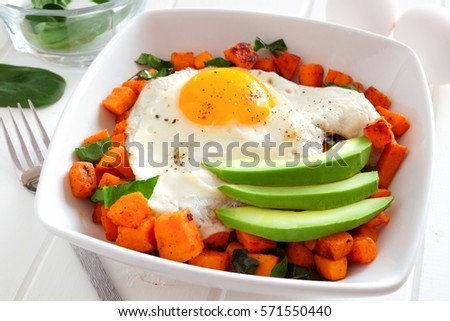 Breakfast nutrient bowl with sweet potato, egg, avocado and spinach, close up table scene