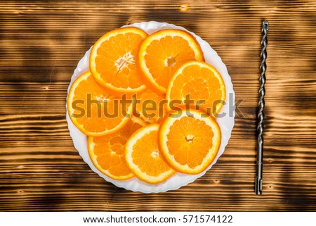 dish of sliced oranges on burnt wooden desk with drill. food pattern